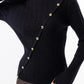 Woman wearing a black sweater with gold buttons